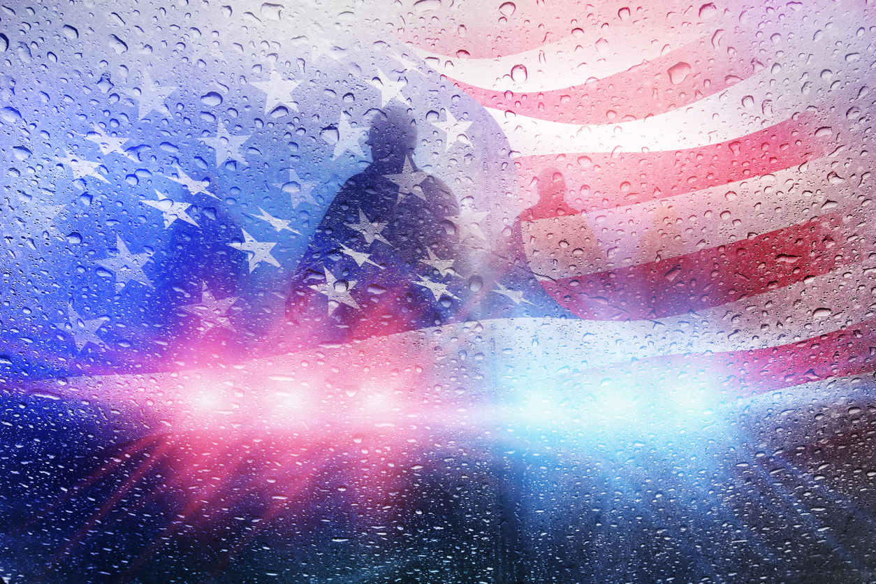 Silhouette of a service member with an American flag and emergency lights